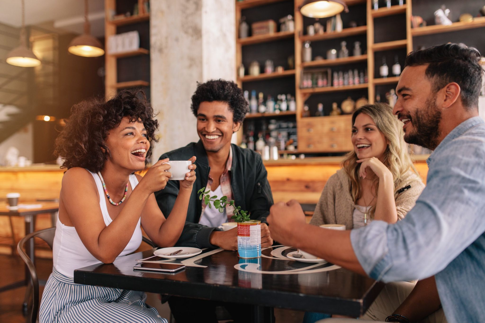 Four friends, immersed in a joyful conversation, savor steaming cups of coffee at a cozy cafe in Chattanooga.